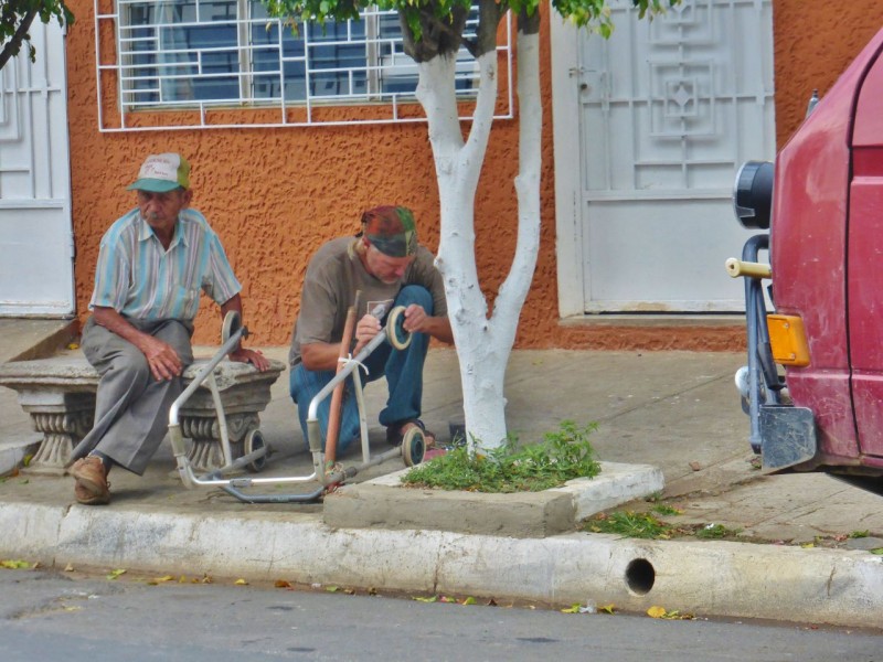 While we waited for our food, I spotted this poor old guy (yeah, the one on the left!) trying to get down the street with his walker, but its wheels kept falling off. I dug some new bolts and nuts out of Charlotte’s stash and soon had the guy motoring down the road.
